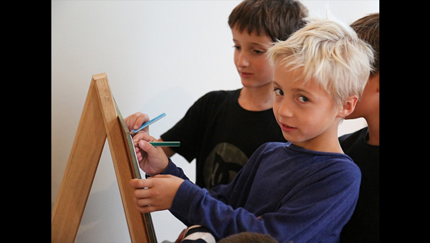 Kinder beim Malen und Schreiben an einer Staffelei